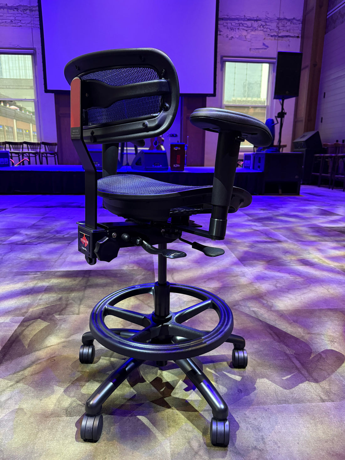 Stealth chair with mesh backrest and adjustable arms under purple studio lighting